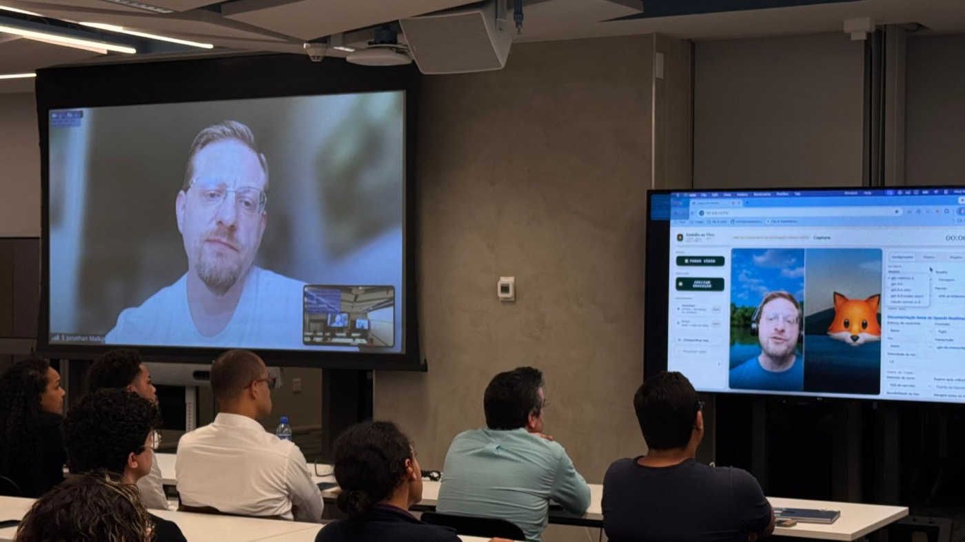 Close view of a live AI assistant demo on screen, showing the presenter alongside a real-time AI avatar.